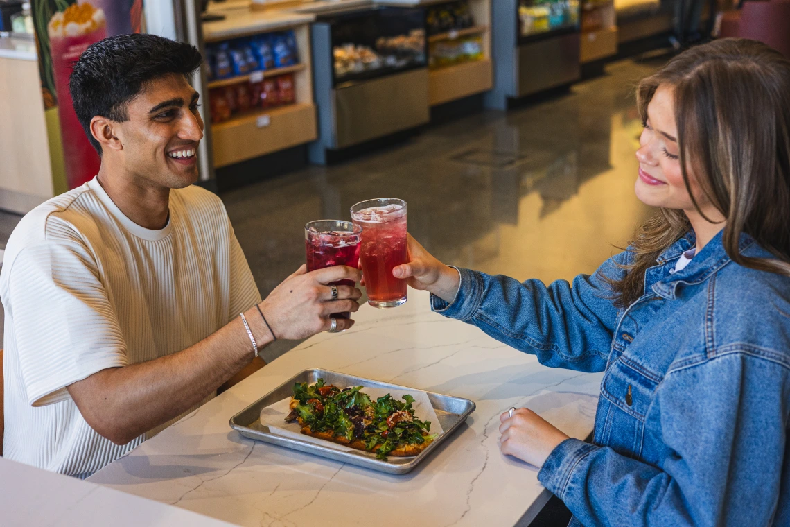 Image of boy on the left sitting across from a girl cheering at cafe bolo
